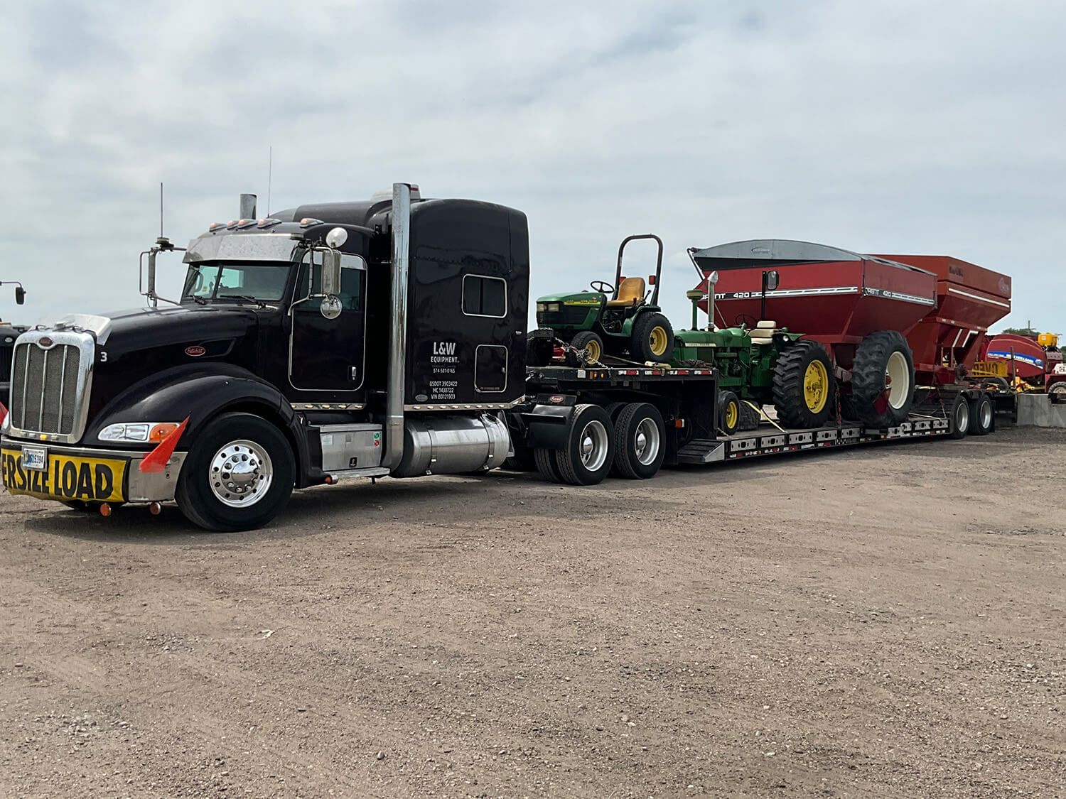 Black Semi carrying various farm equipment